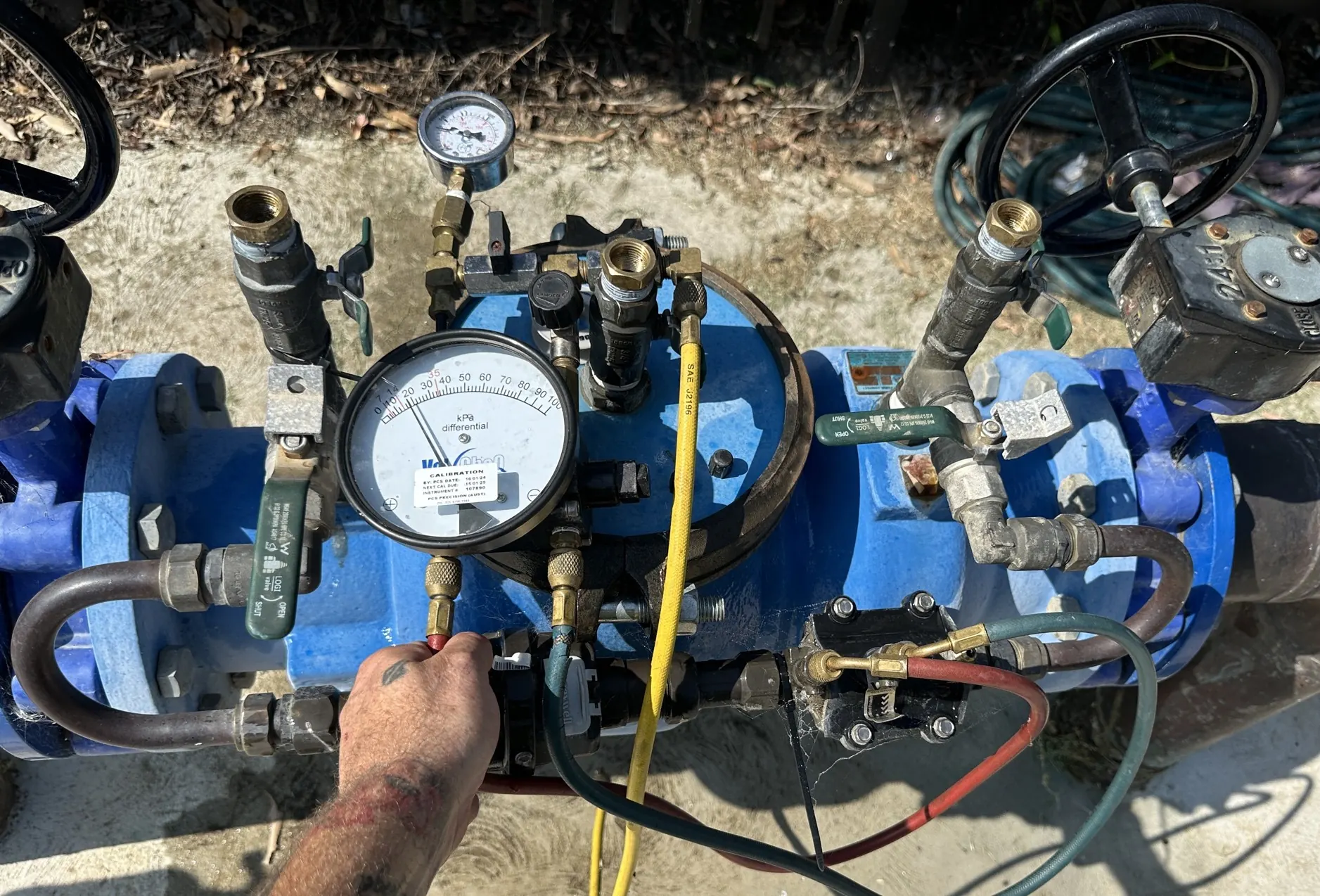Certified plumber testing a backflow prevention device on site