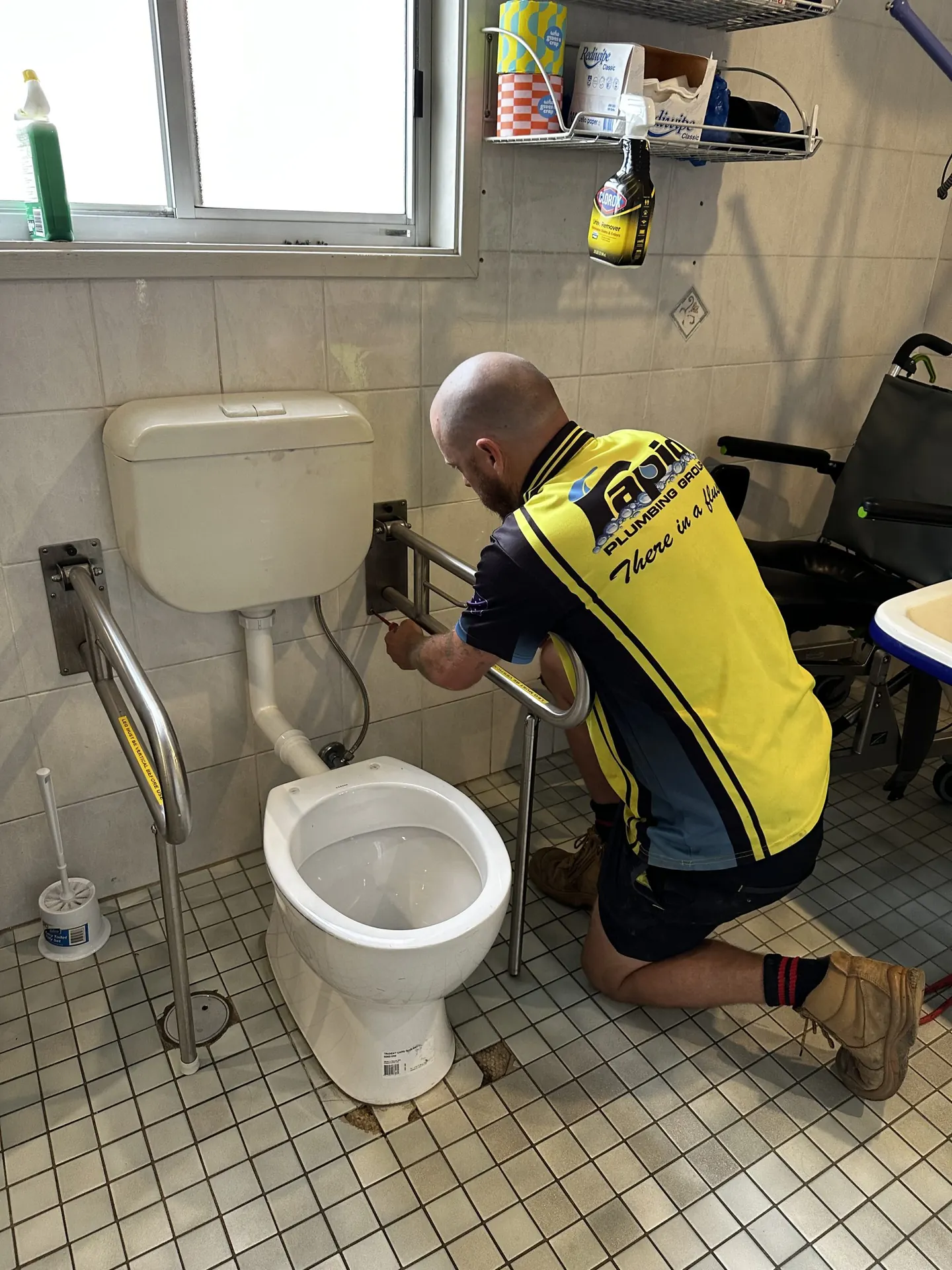 Licensed plumber installing grab rails around a toilet