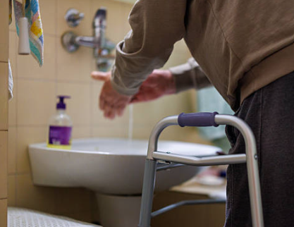 NDIS participant using accessible basin with lever tapware and walking frame